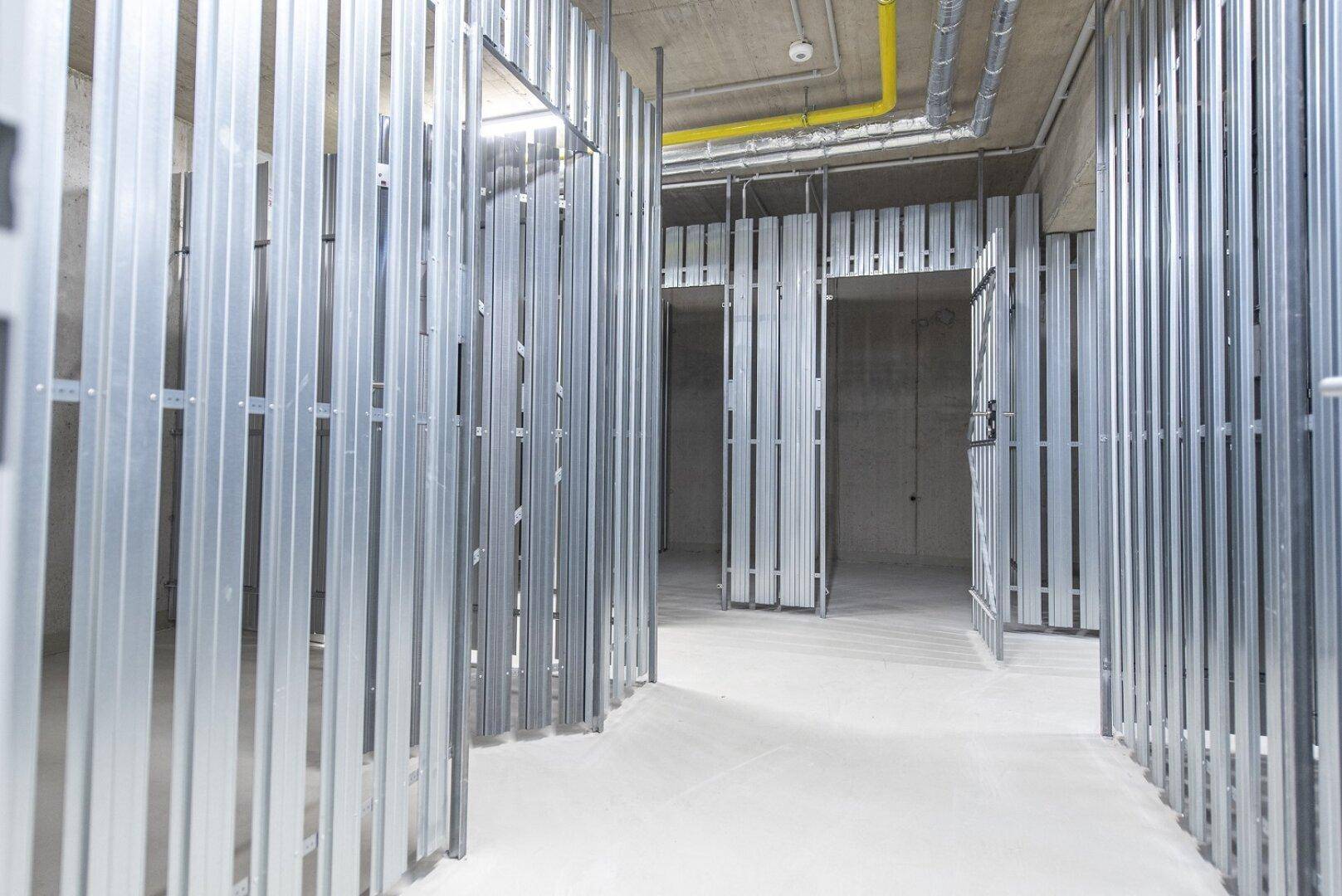 Abstellräume im Kellerbereich mit Metallabtrennungen und Betonboden, ideal für zusätzlichen Stauraum.