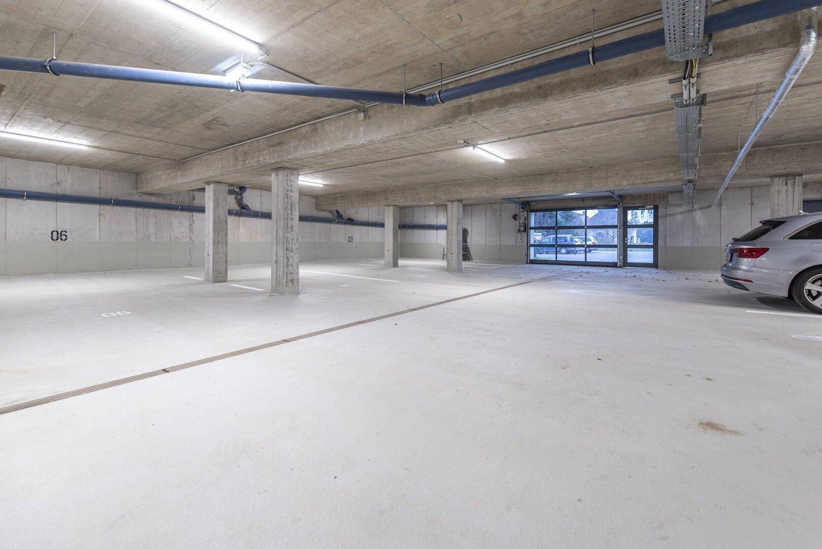 Geräumige Tiefgarage mit Betonstützen und ausreichend Stellplätzen für Fahrzeuge.