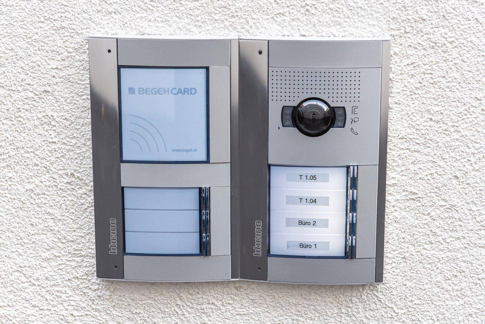 Moderne Gegensprechanlage mit Kamera und Klingeltasten an der Außenwand des Gebäudes.