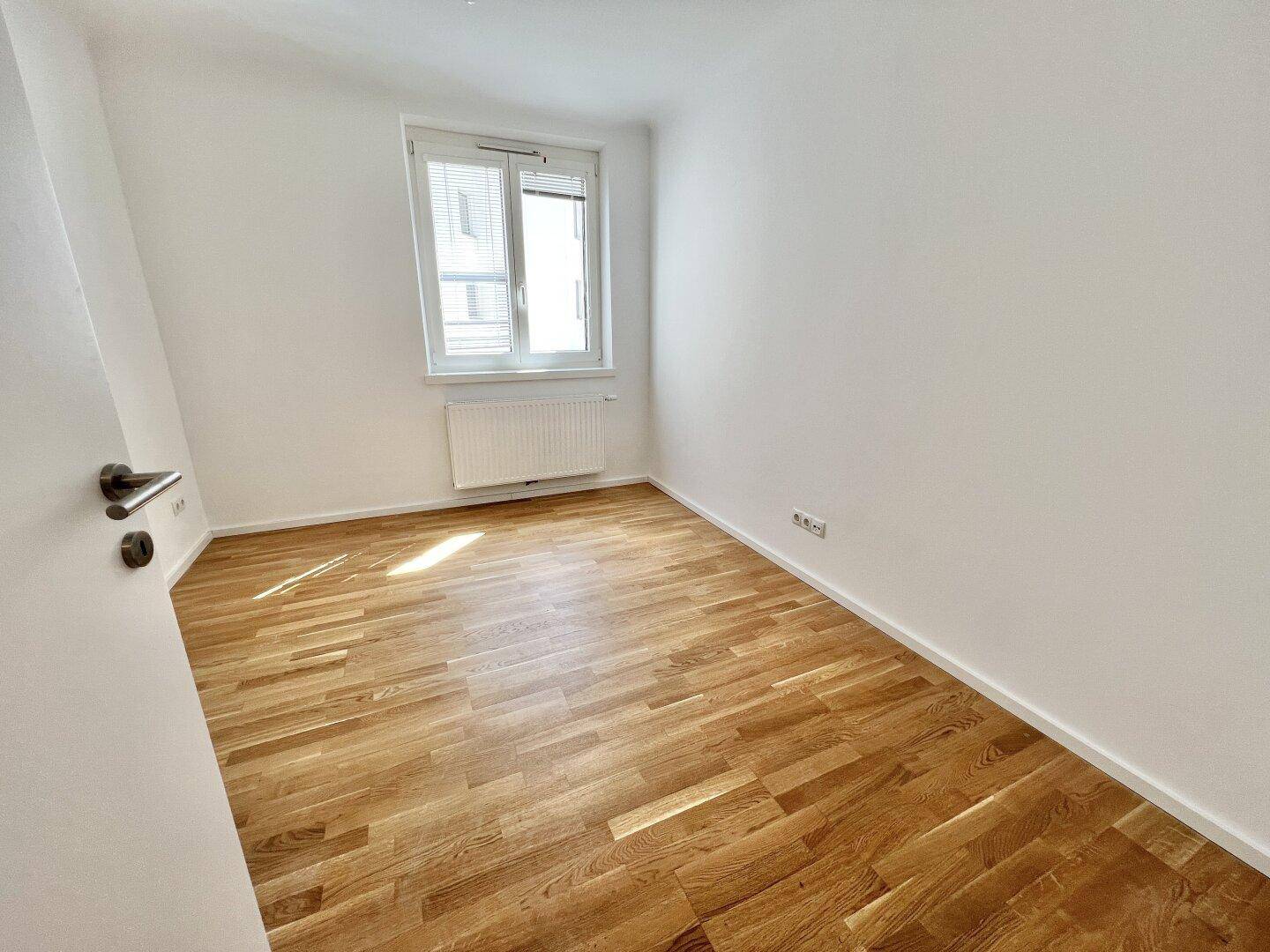 Helles Zimmer mit Parkettboden und einem Fenster, ideal als Schlaf- oder Arbeitszimmer nutzbar.