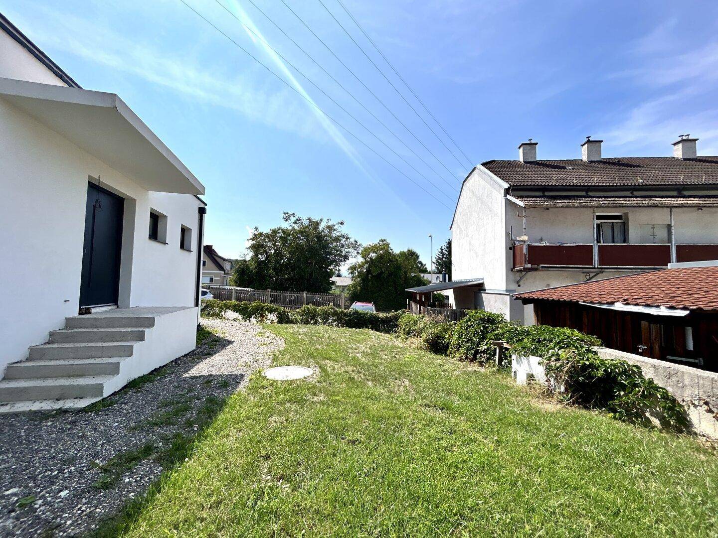 Gartenbereich mit Rasenfläche und angrenzendem Neubau in ländlicher Umgebung.