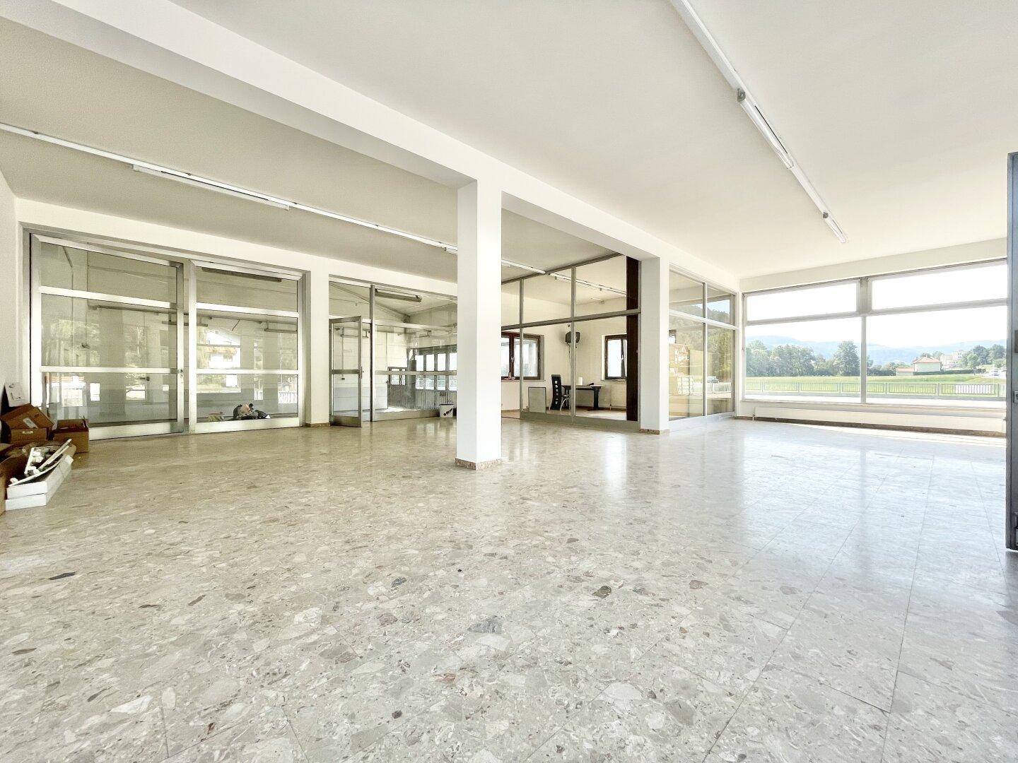 Heller, offener Gewerberaum mit Säulen, großen Fenstern und Terrazzoboden, ideal für Büros.