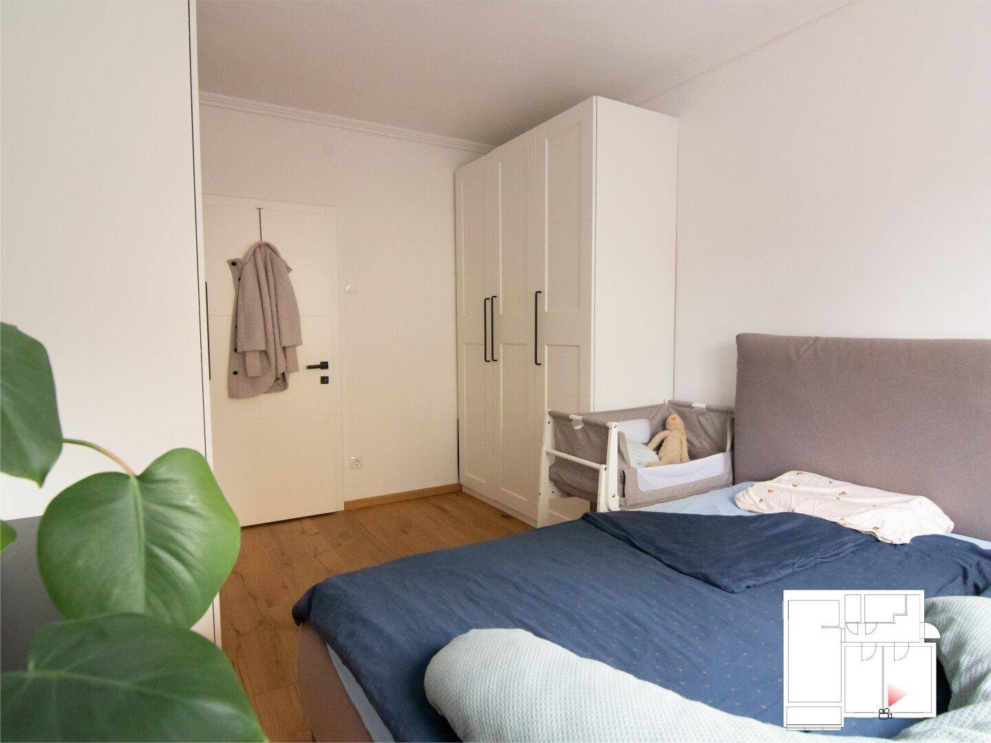 Schlafzimmer mit weißem Einbauschrank, Doppelbett und Holzfußboden.