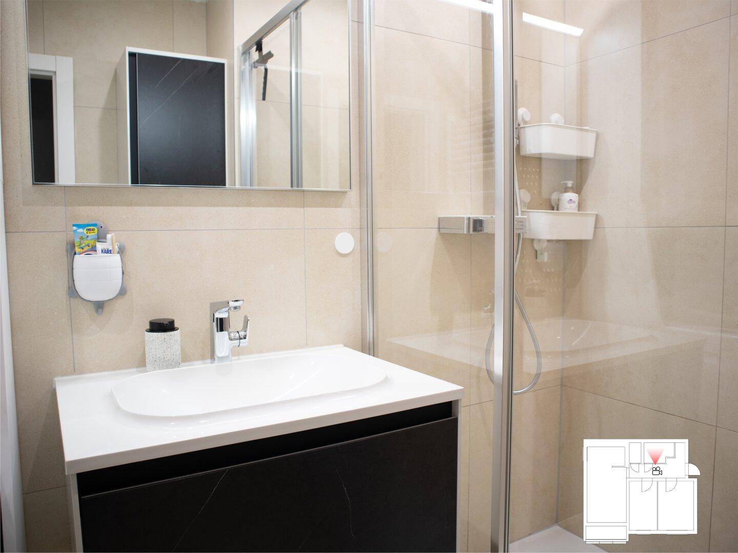 Modernes Badezimmer mit Duschkabine, Waschbecken und beigefarbenen Fliesen.