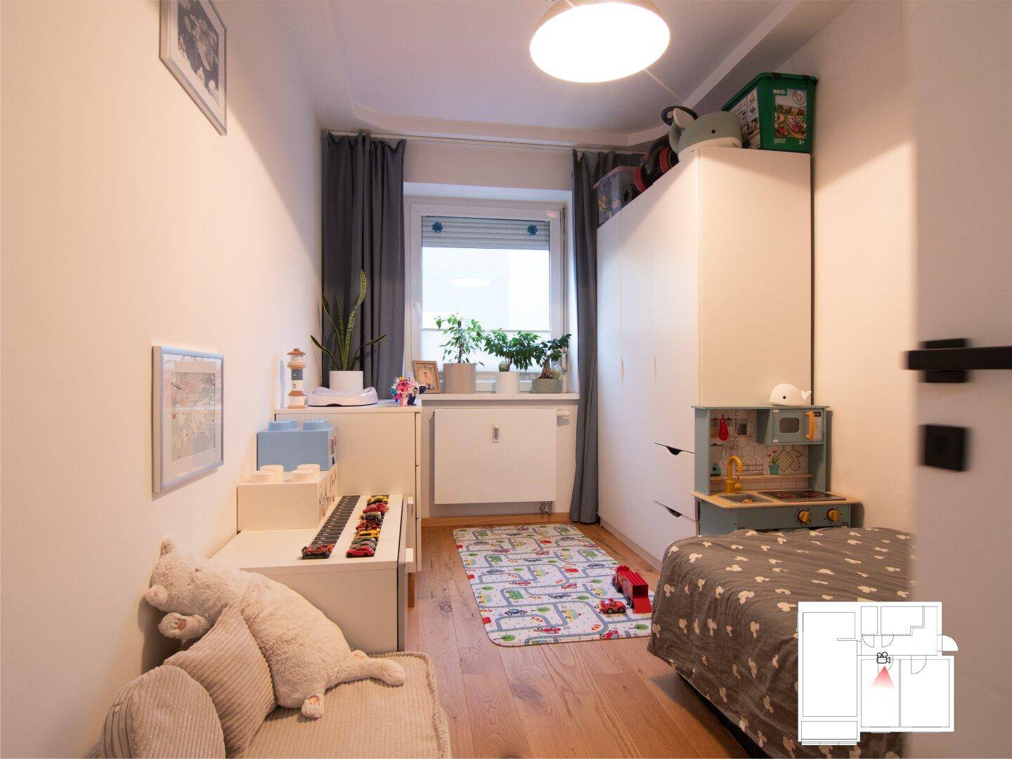 Helles Kinderzimmer mit Spielbereich, Bett und farbenfroher Dekoration.