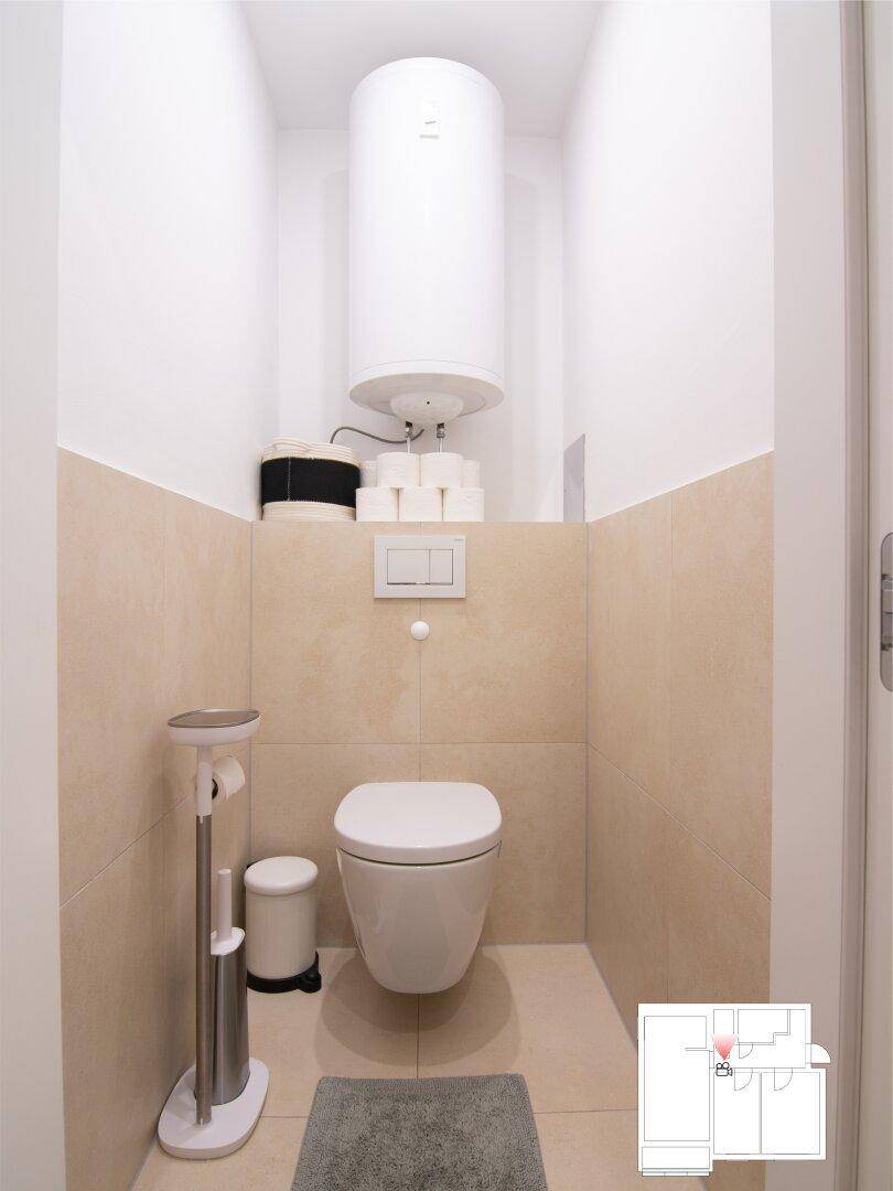 Kleines, separates WC mit Wand-WC und beigefarbenen Wand- und Bodenfliesen.