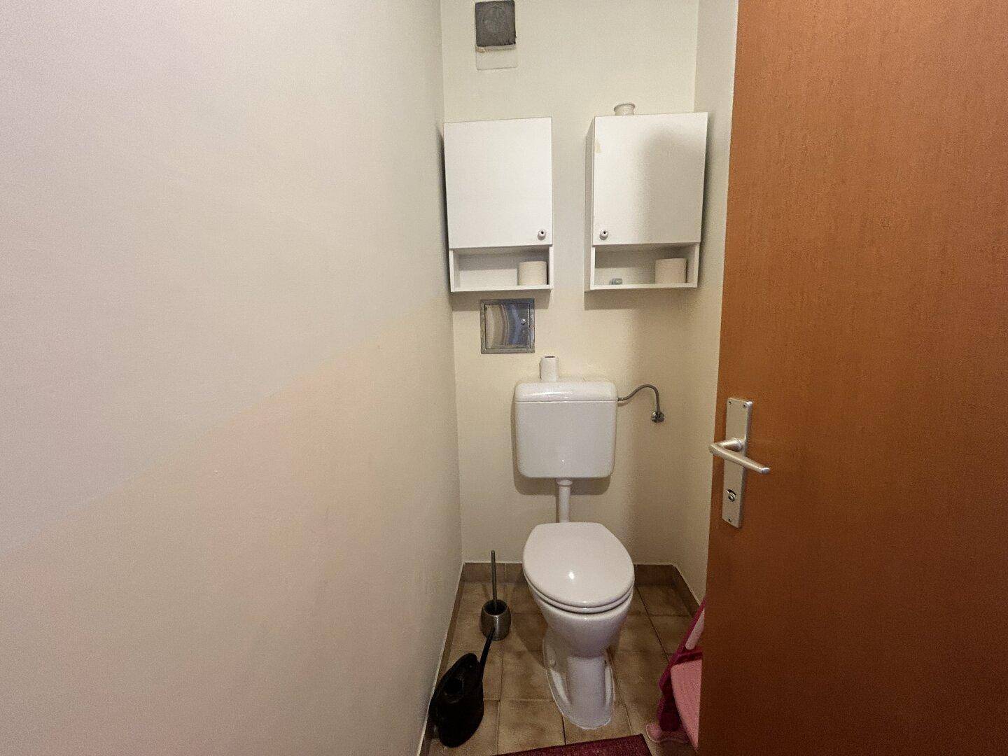Separates WC mit Toilette und Wandregalen für zusätzlichen Stauraum.