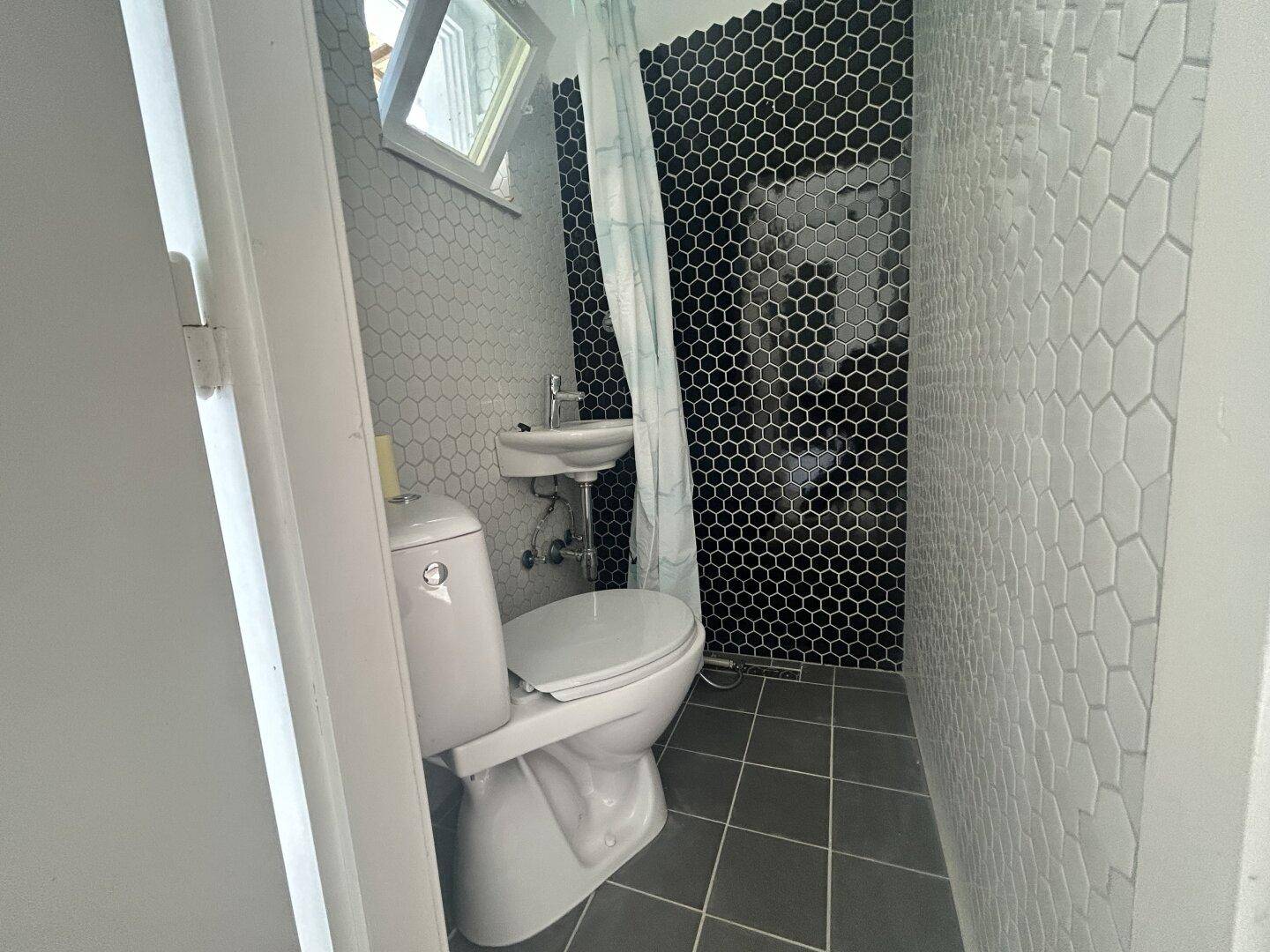 Modernes Badezimmer mit schwarzen und weißen sechseckigen Fliesen und Dusche.
