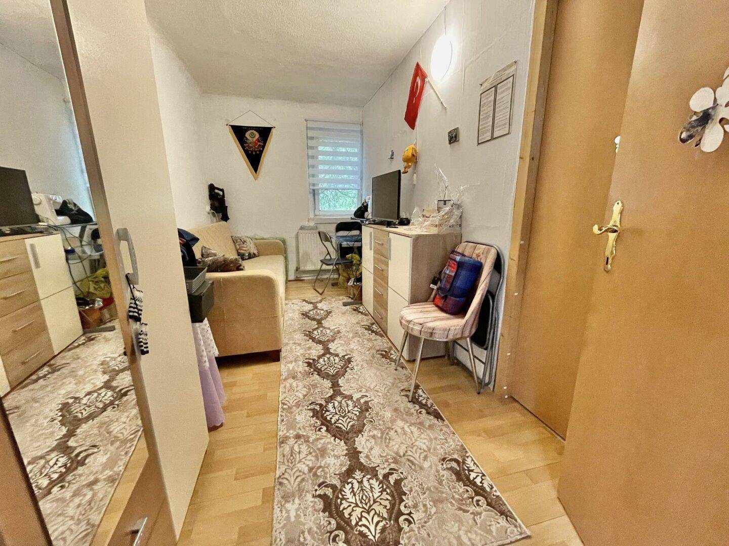 Gemütliches Zimmer mit Sofa, Fernseher und Teppichboden, ideal als Gäste- oder Arbeitszimmer.