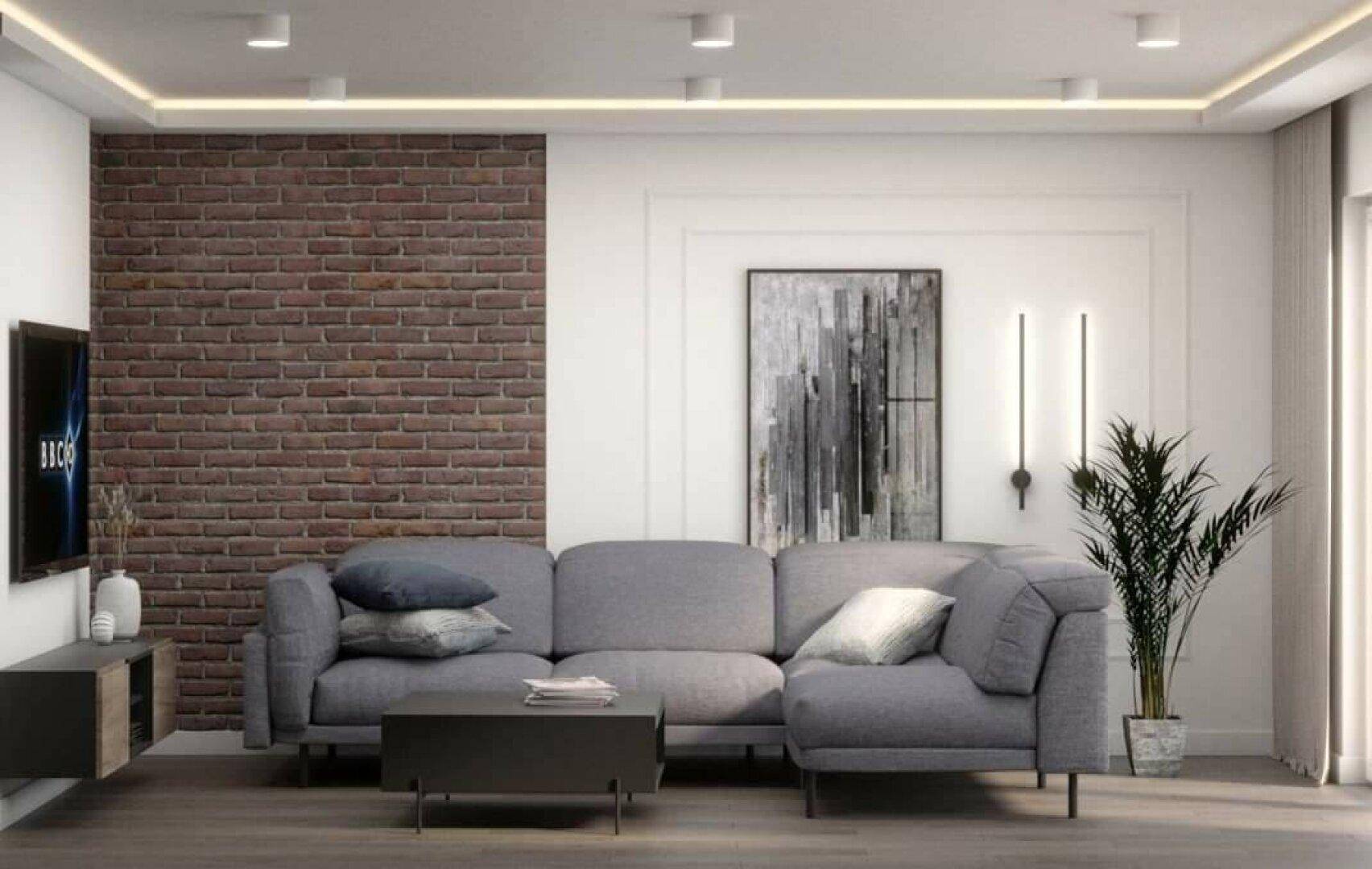 Gemütliches Wohnzimmer mit grauer Eckcouch, Ziegelwand und moderner Beleuchtung.