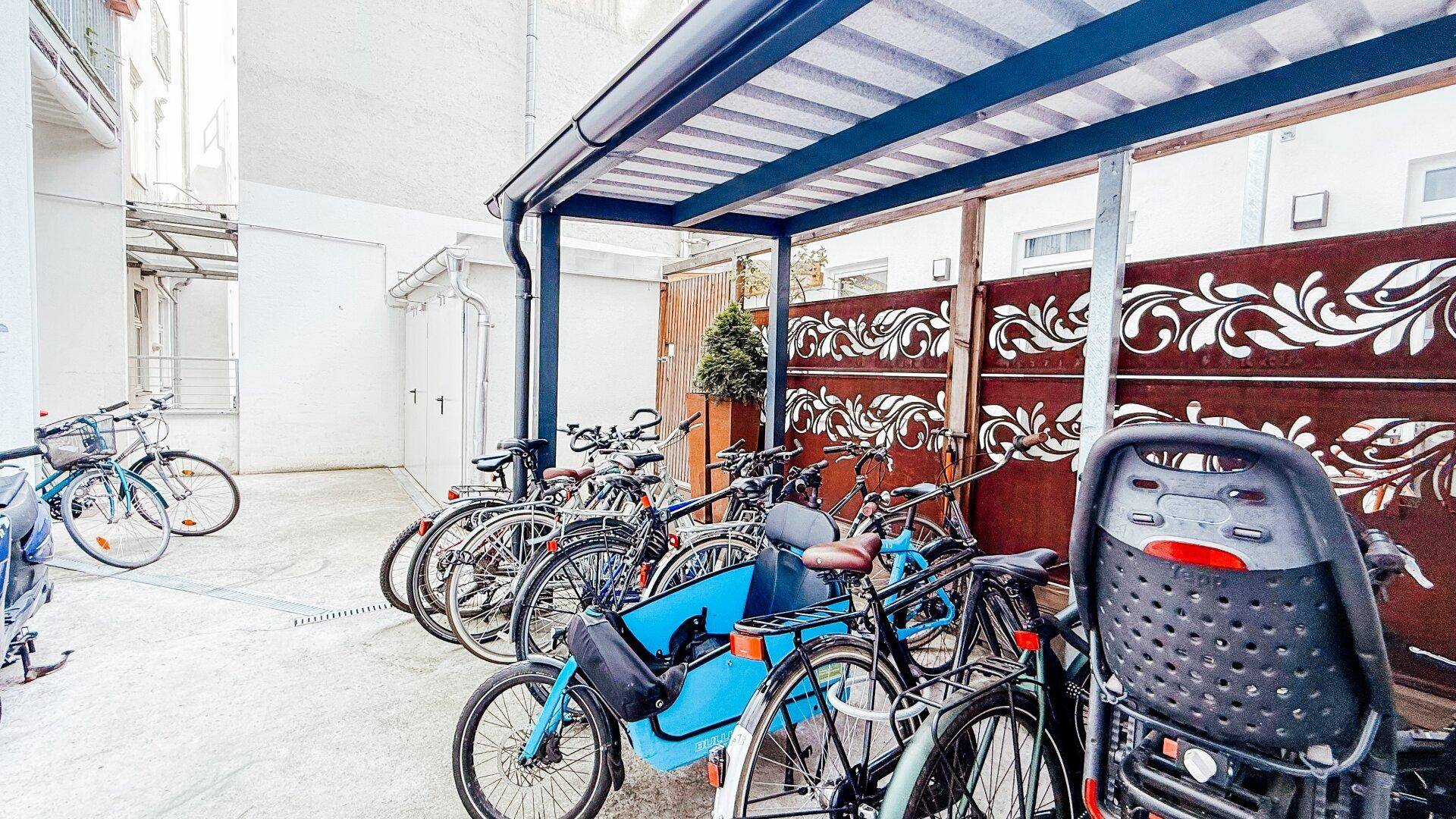 Überdachter Fahrradabstellplatz im Freien mit dekorativen Seitenwänden.