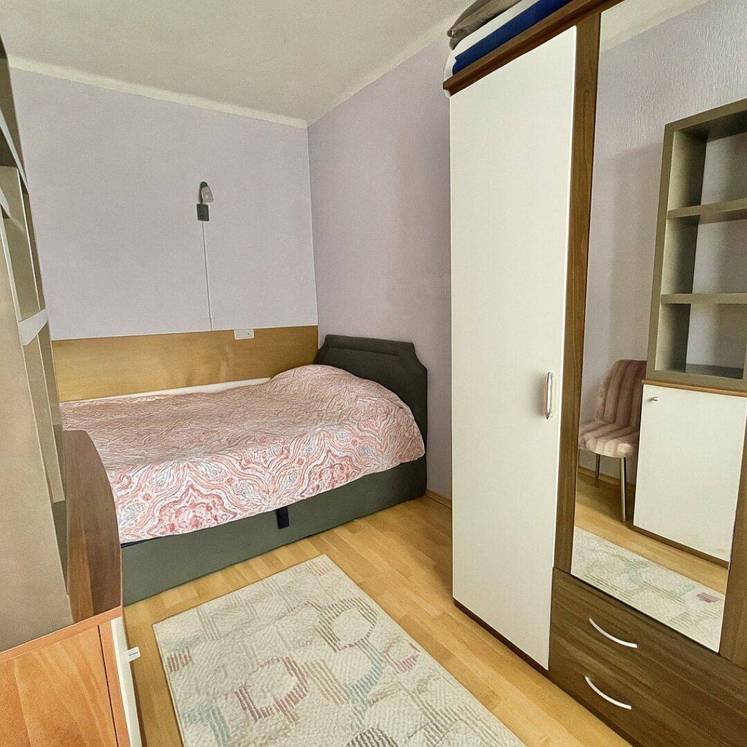 Schlafzimmer mit Doppelbett, Kleiderschrank und hellem Holzboden in ruhiger Atmosphäre.