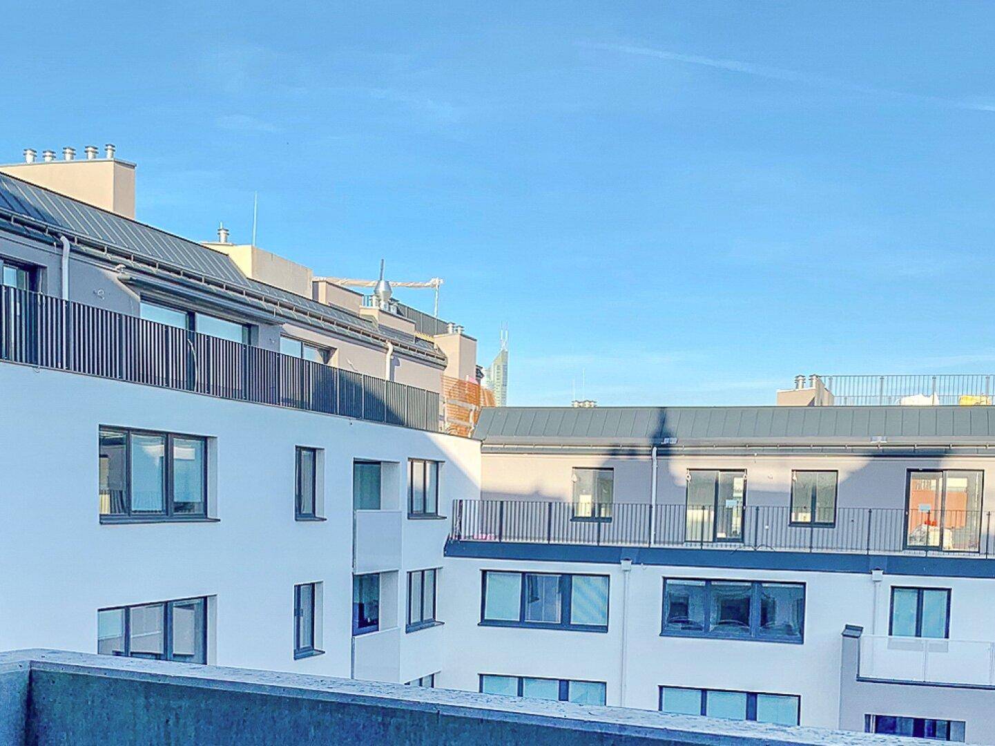 Moderne Wohngebäude mit Balkonen und klarem blauen Himmel im Hintergrund.