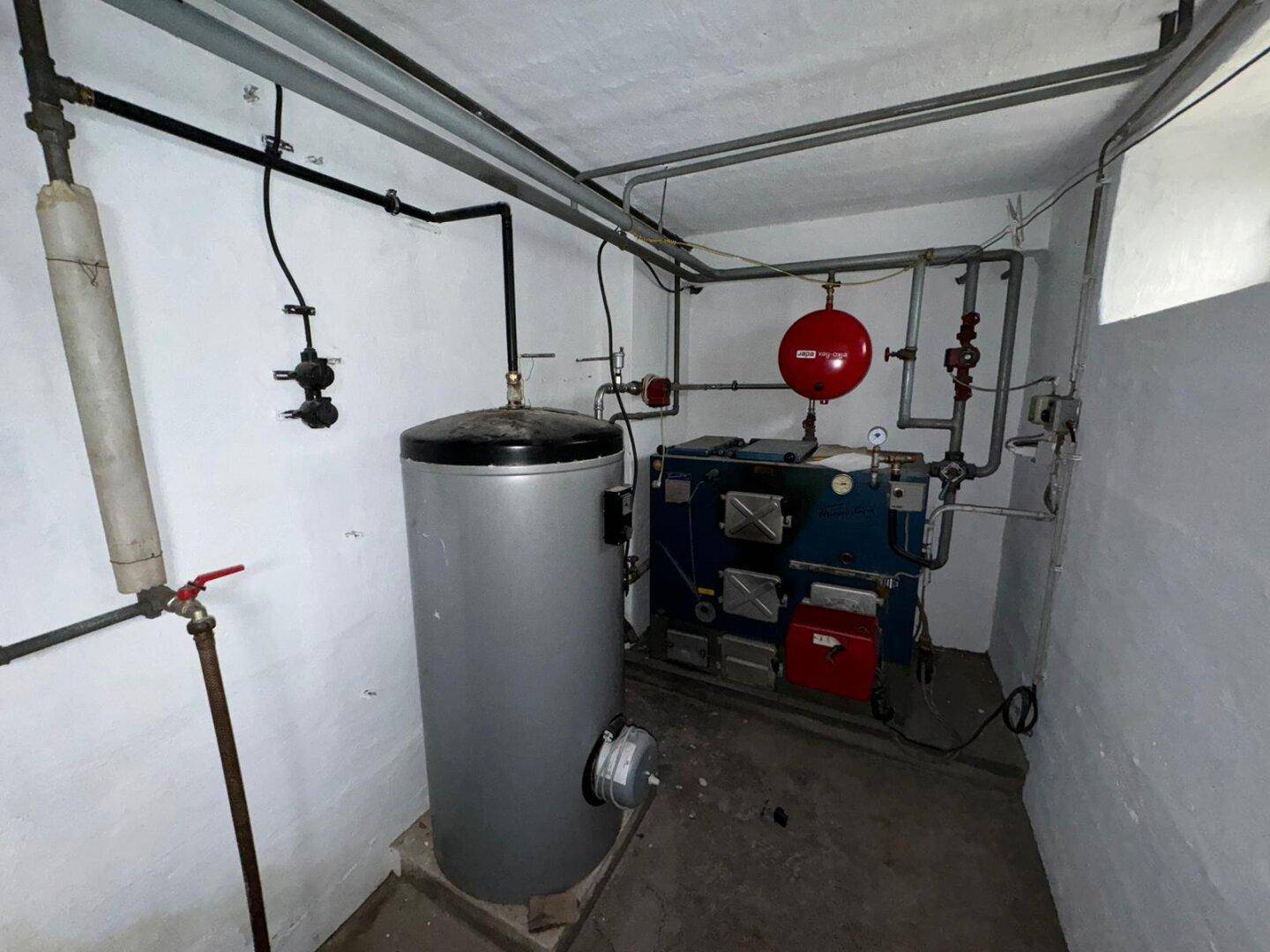 Heizungsraum im Keller mit Warmwasserspeicher und zentraler Heizungsanlage.
