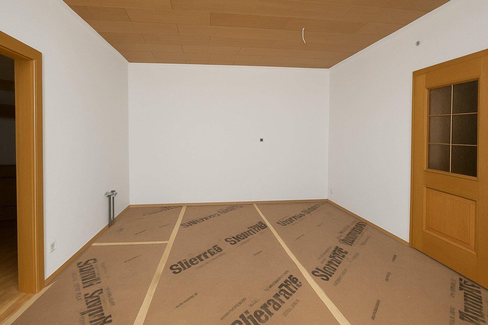 Leerer Raum mit vorbereitetem Boden für neue Verlegung und Holzdecke.