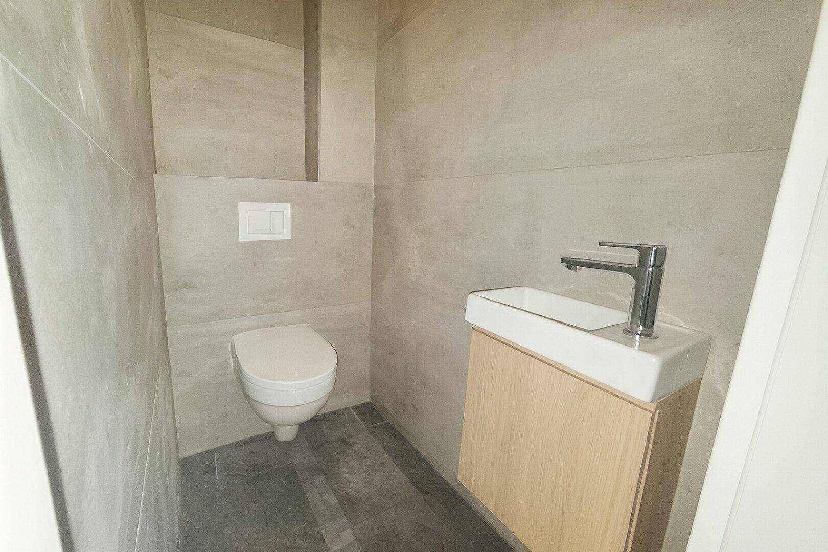 Modernes Gäste-WC mit wandhängender Toilette und kleinem Waschbecken.