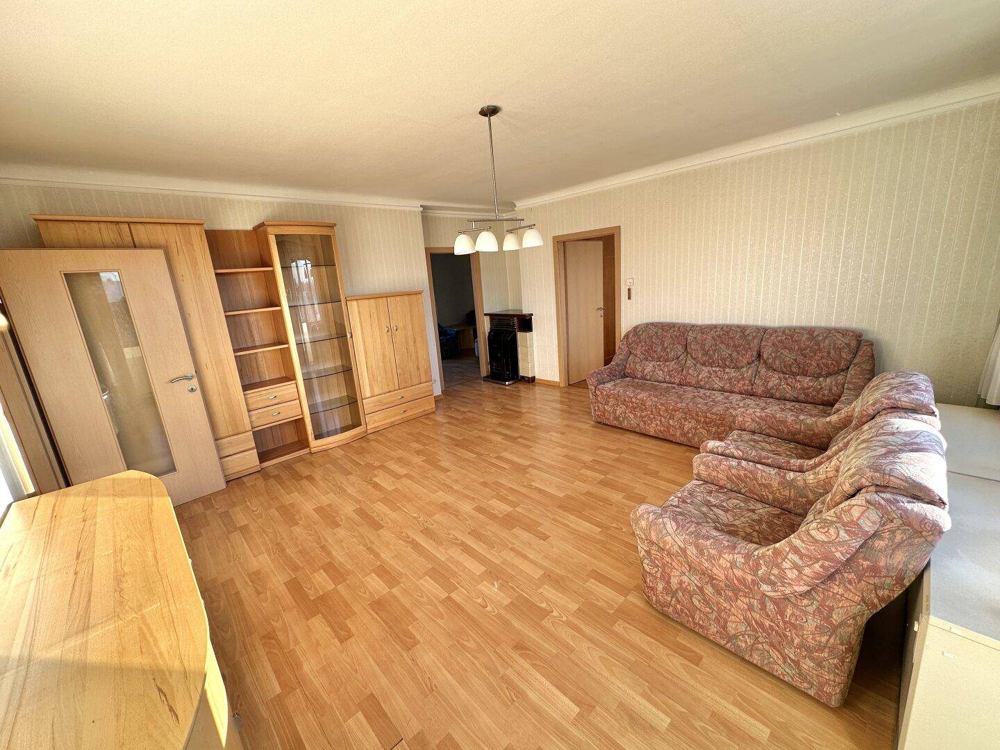 Geräumiges Wohnzimmer mit Laminatboden und traditionellen Holzmöbeln, ideal für gesellige Stunden.