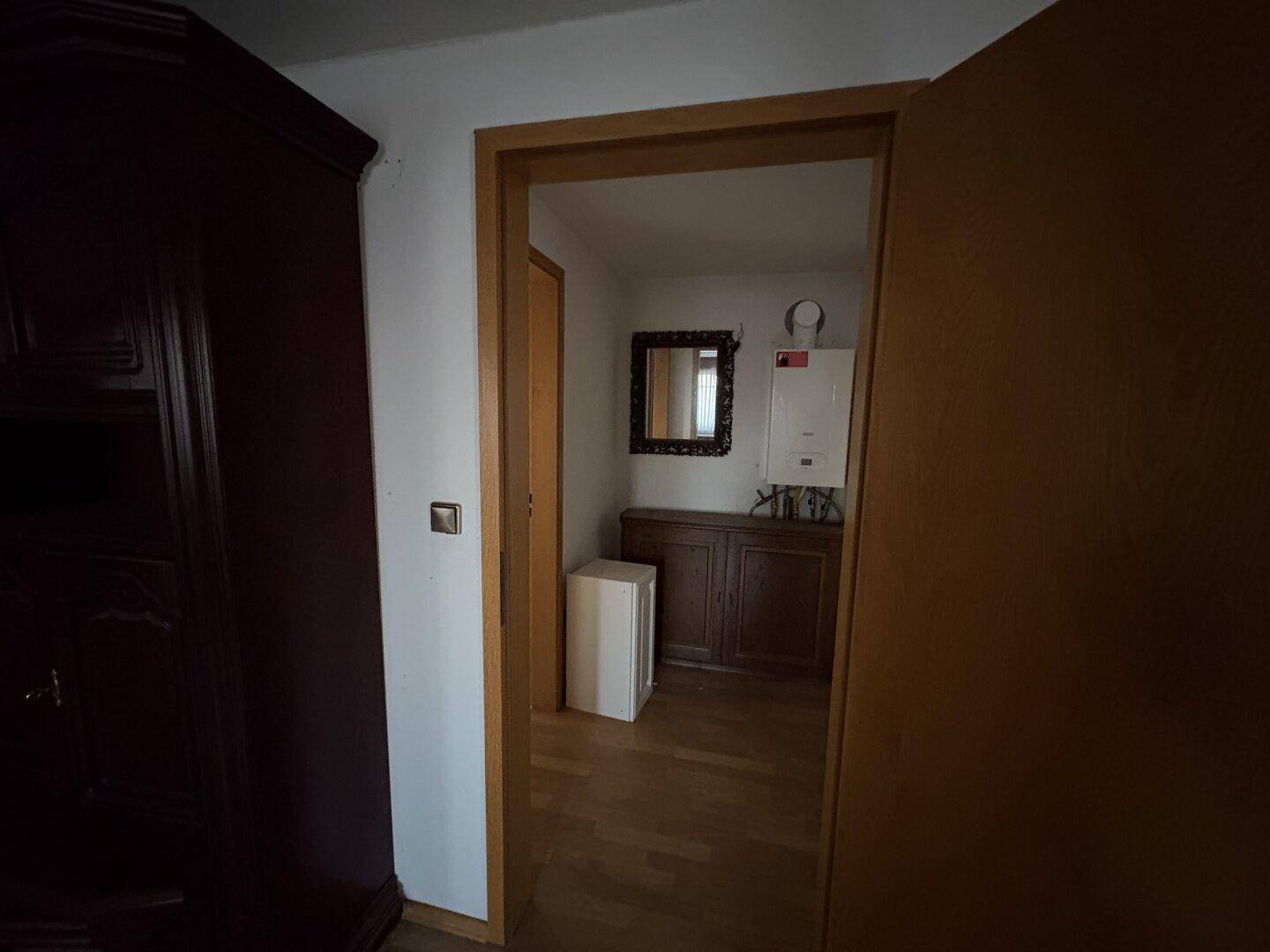 Kleiner Flur mit Holzschrank und an der Wand montiertem Heizkessel.