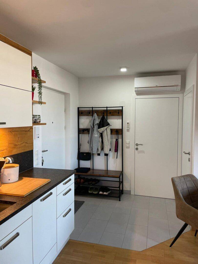 Eingangsbereich mit Garderobe und Fliesenboden, angrenzend an die moderne Küche und Wohnbereiche.