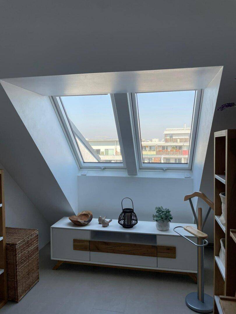 Heller Raum mit zwei großen Dachfenstern, die viel natürliches Licht hereinlassen und Ausblick bieten.