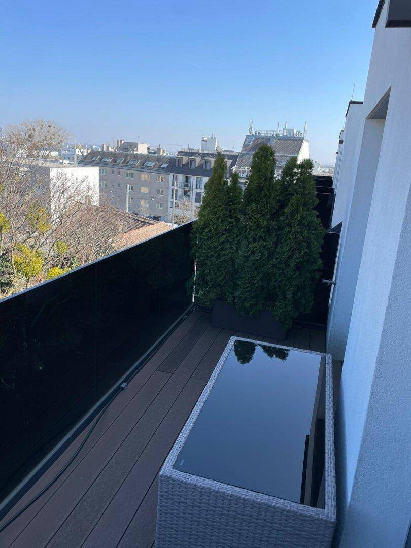 Sonnige Dachterrasse mit Holzbelag, Pflanzen und Sitzgelegenheiten, ideal zum Entspannen im Freien.