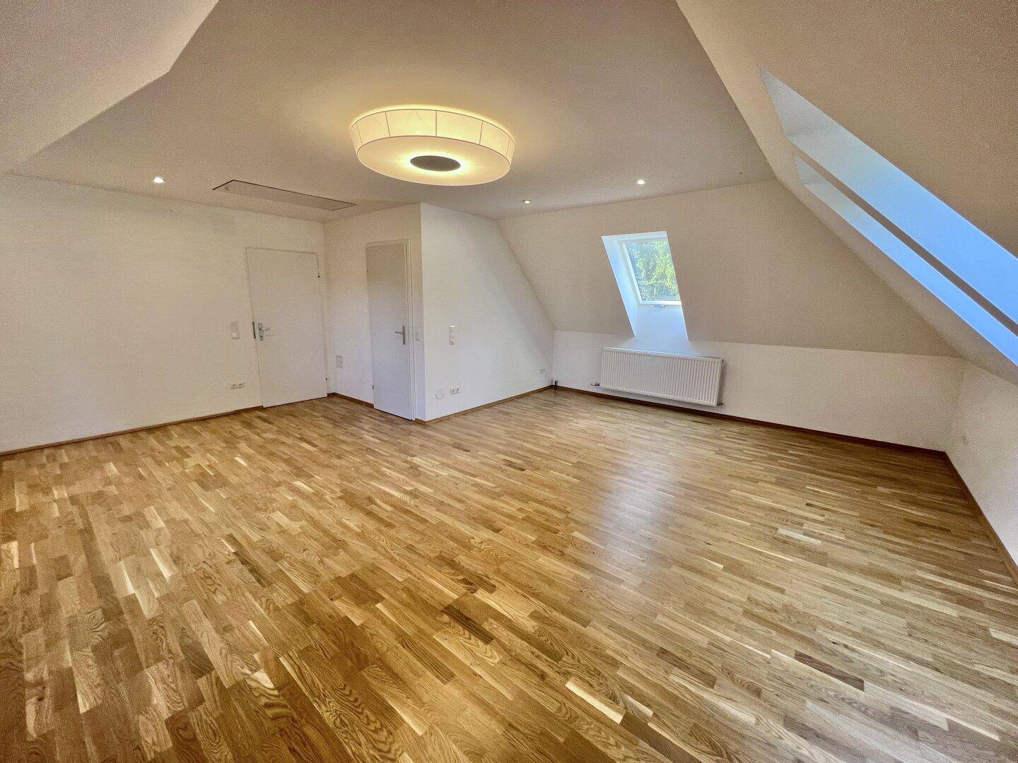 Geräumiges Schlafzimmer im Dachgeschoss mit Holzboden und Dachfenster, hell und freundlich.