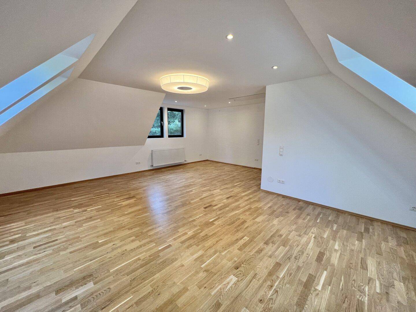 Helles Schlafzimmer im Dachgeschoss mit Holzboden und Fenstern, bietet viel Platz.