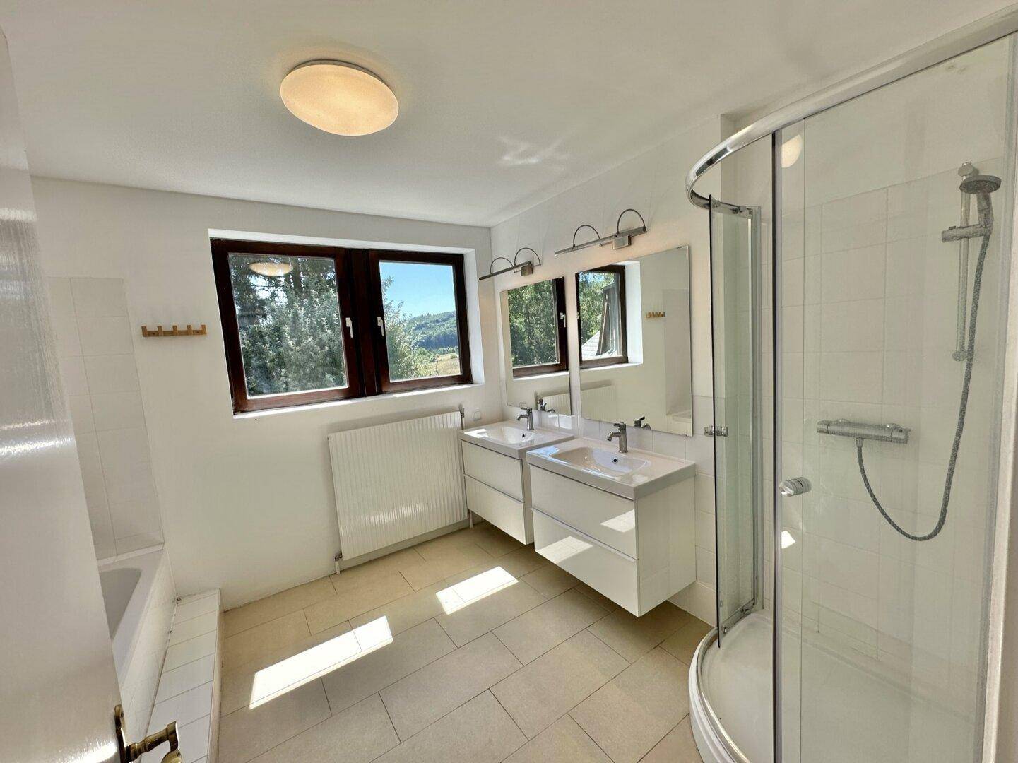 Geräumiges Badezimmer mit zwei Waschbecken, Dusche und Badewanne, hell und modern.