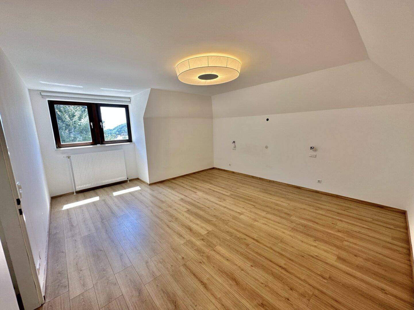 Helles Schlafzimmer mit Holzboden und Fenster, bietet viel natürliches Licht.