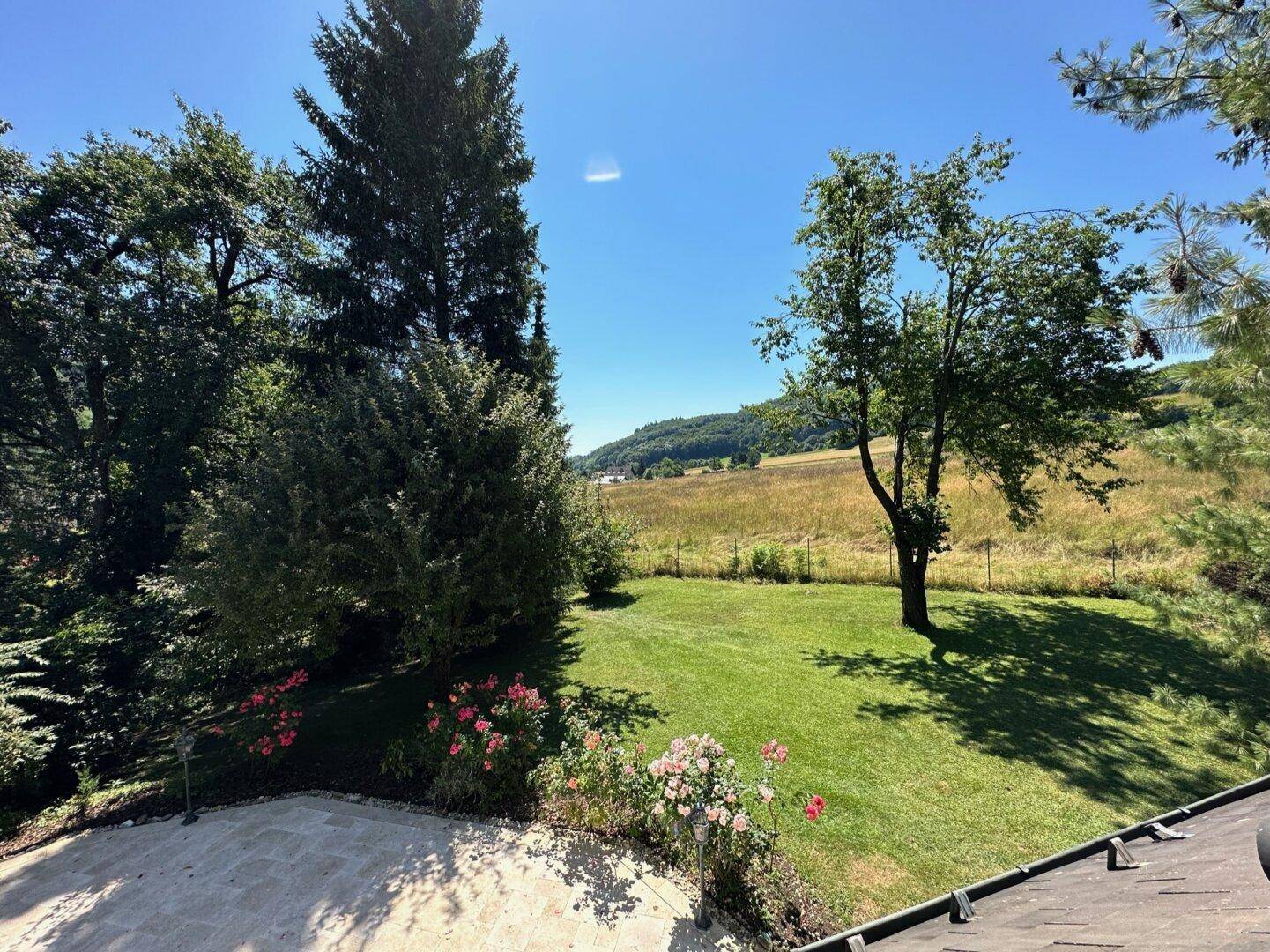 Großer Gartenbereich mit Rasenfläche und weitem Blick auf die umliegende Landschaft und Felder.