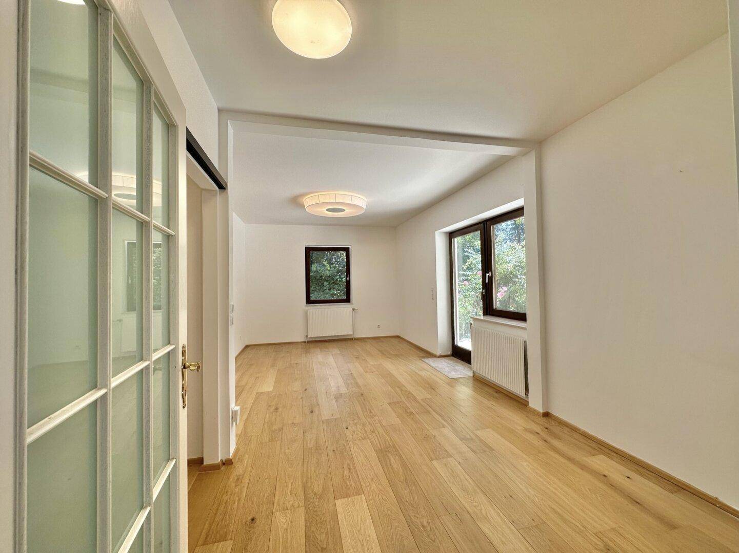 Heller Raum mit Holzboden und großen Fenstern, vielseitig nutzbar.