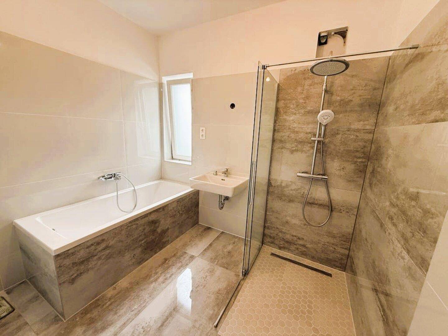 Modernes Badezimmer mit Badewanne, Dusche und Fenster.