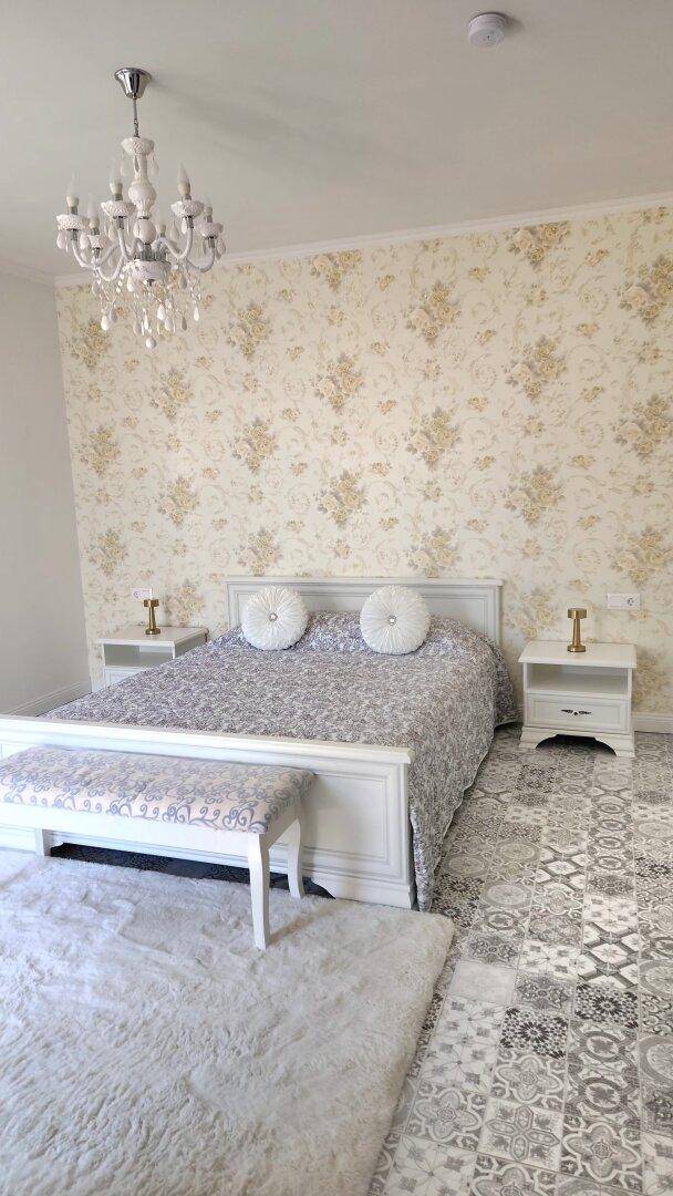 Elegantes Schlafzimmer mit Doppelbett, gemusterter Tapete und dekorativem Fliesenboden.