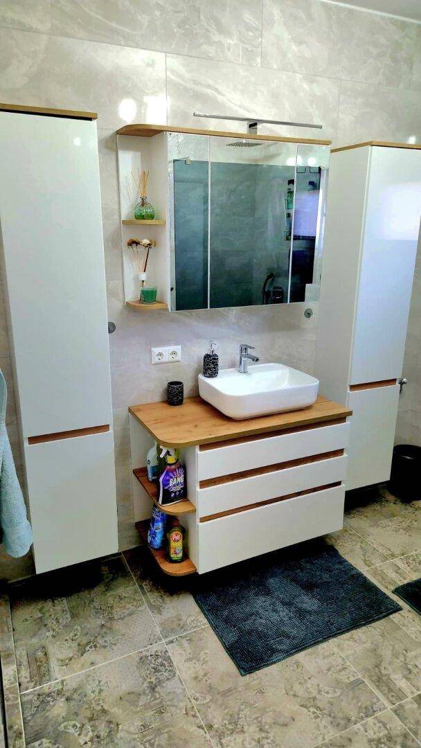 Modernes Badezimmer mit stilvollem Waschtisch, Spiegelschrank und Fliesenboden.