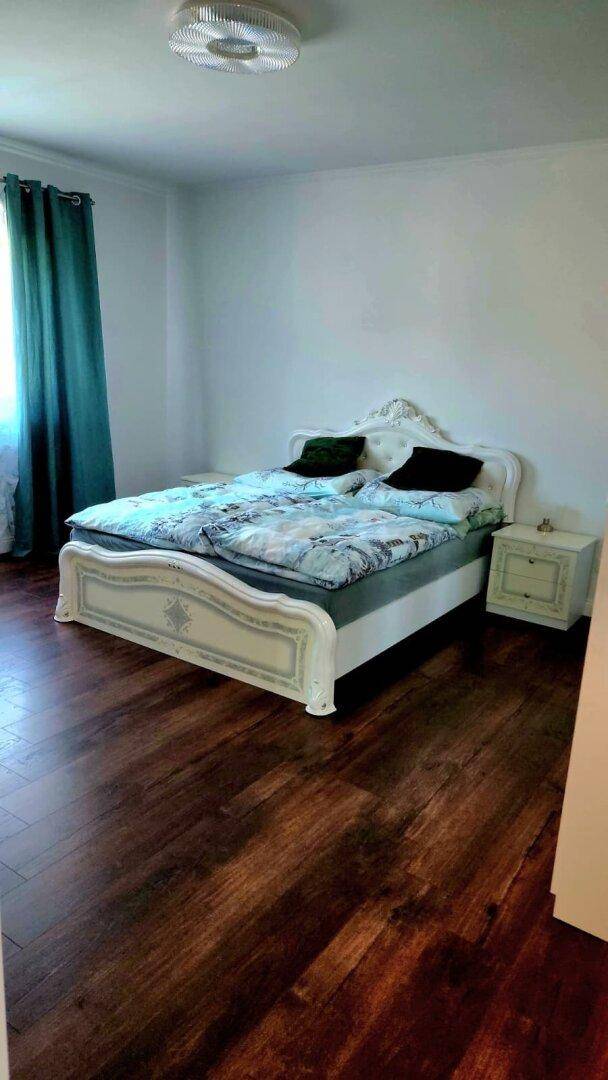 Geräumiges Schlafzimmer mit Doppelbett und dunklem Holzfußboden.