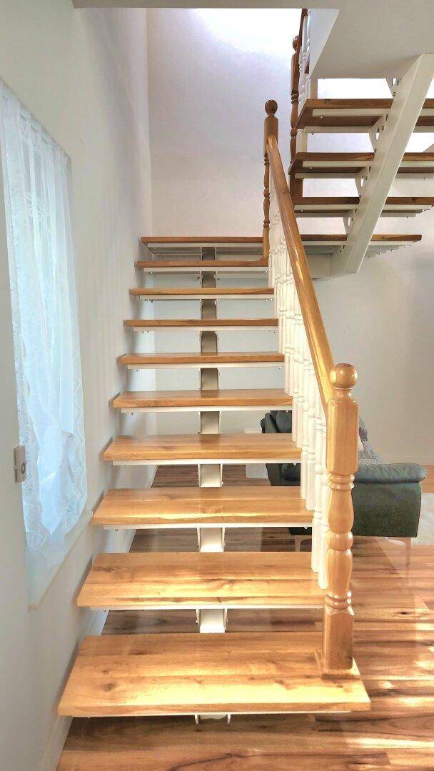 Elegante Holztreppe mit weißem Geländer, die die Stockwerke miteinander verbindet.