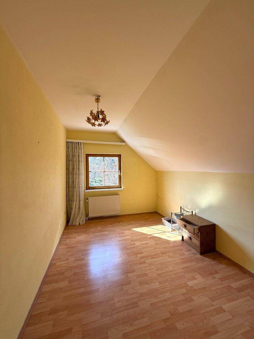 Helles Schlafzimmer im Dachgeschoss mit Schrägen und Laminatboden, bereit zur individuellen Gestaltung.