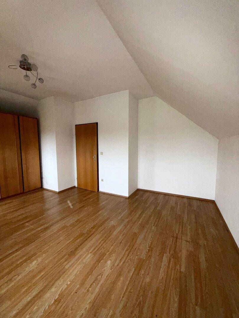 Schlafzimmer im Dachgeschoss mit Laminatboden, Schrägen und praktischem Einbauschrank.