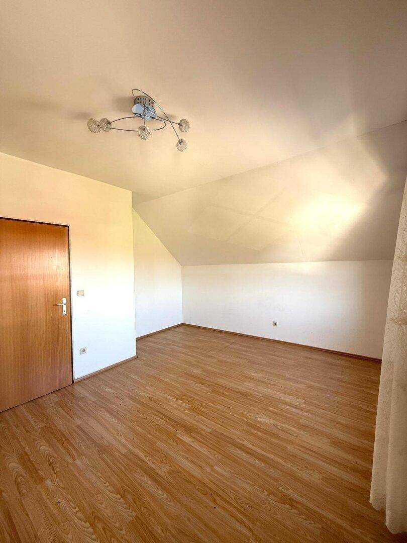 Geräumiges Schlafzimmer im Dachgeschoss mit Laminatboden und Dachschrägen, vielseitig nutzbar.
