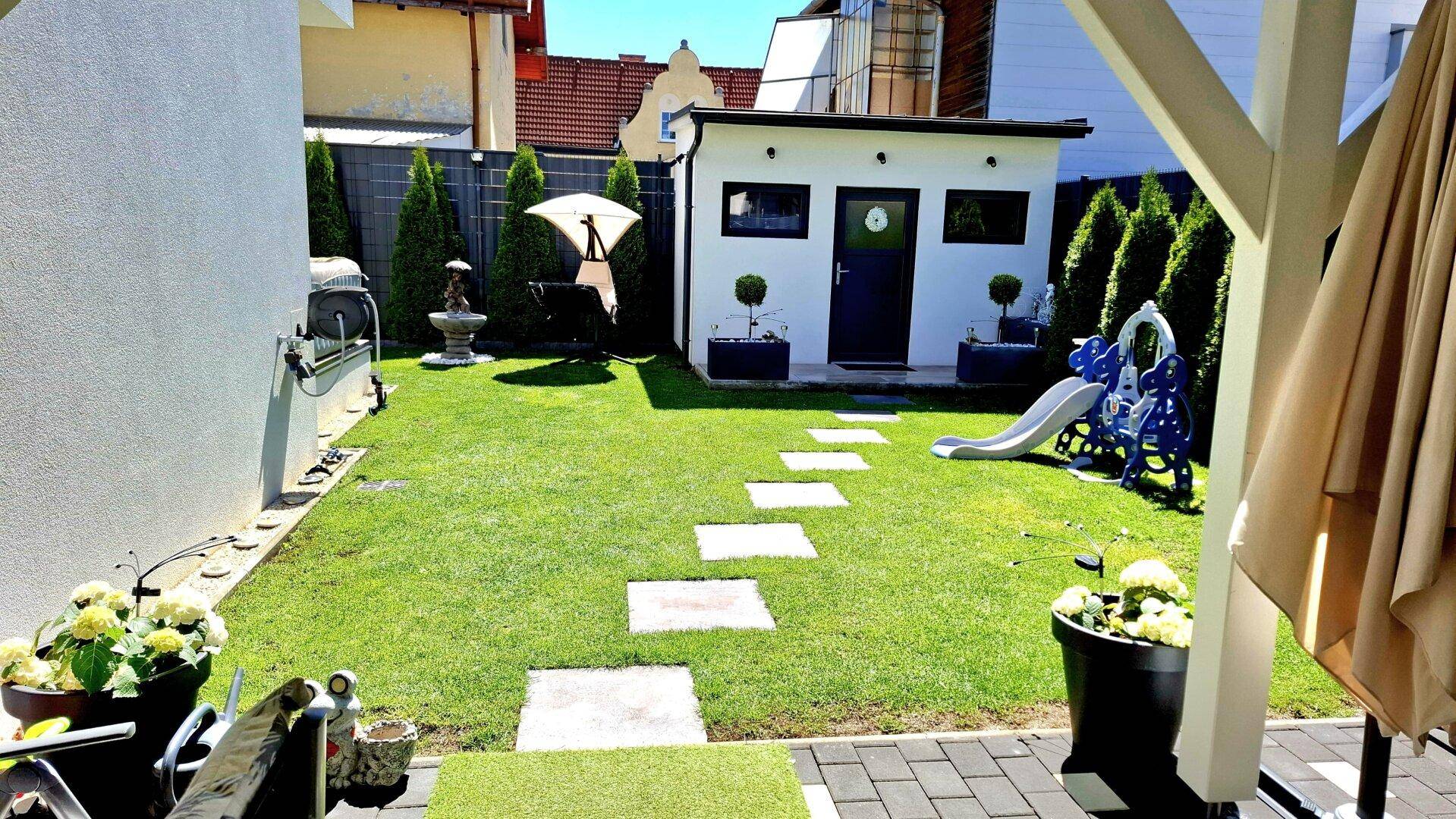 Großer Garten mit Spielgeräten, Gartenhaus und Grillbereich für Familienaktivitäten.