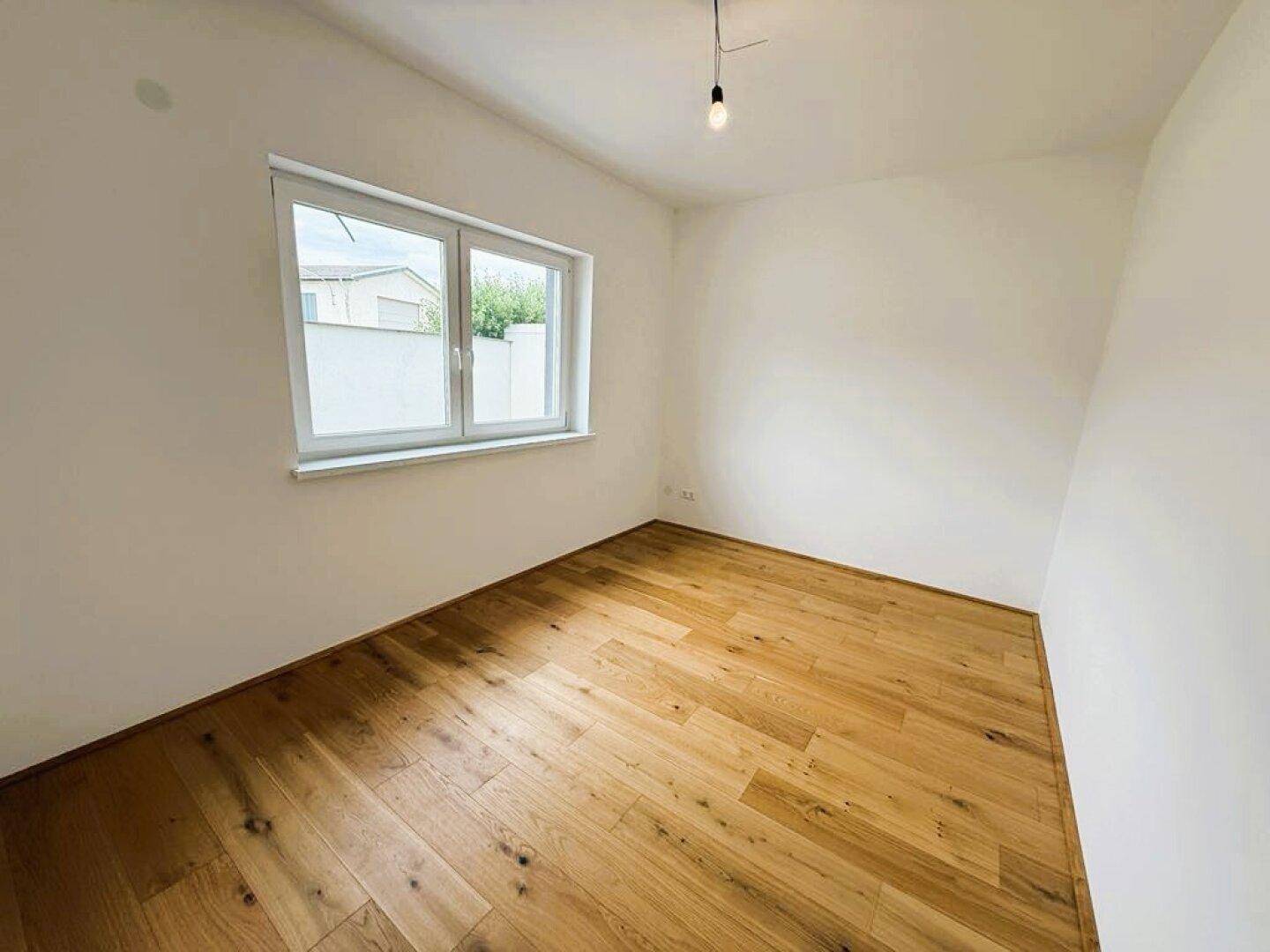 Leeres Zimmer mit Holzboden und einem Fenster, perfekt für ein Kinderzimmer oder Büro.