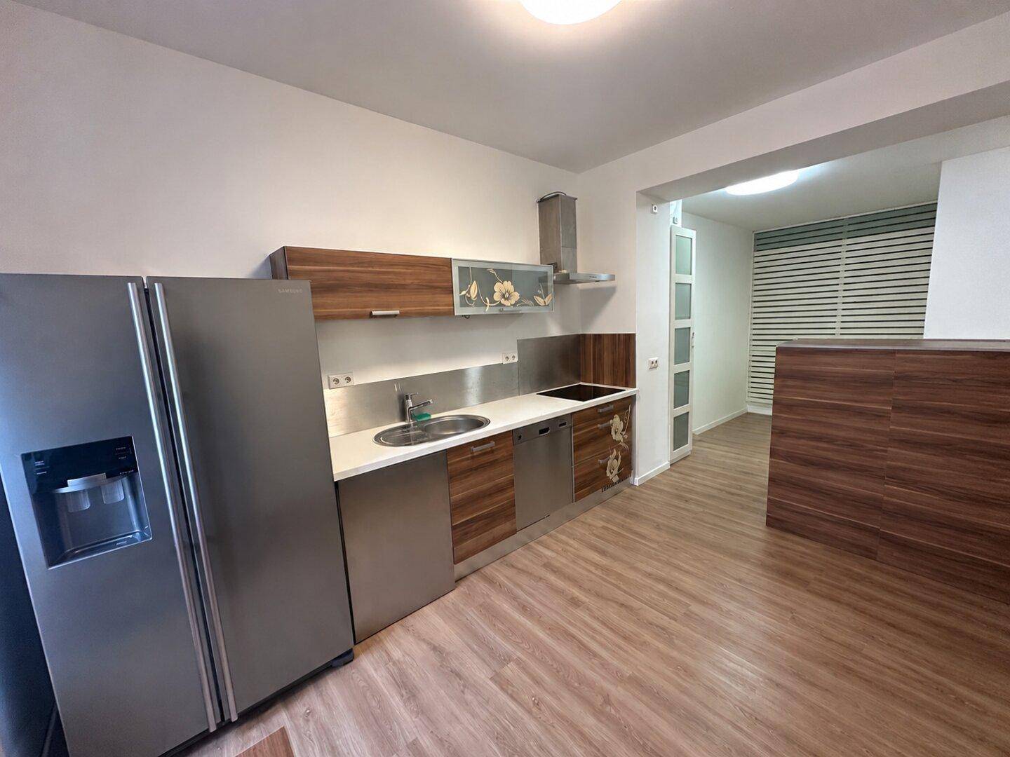 Offene Küche mit Holzfronten und Edelstahlgeräten, die in einen angrenzenden Wohnbereich übergeht.