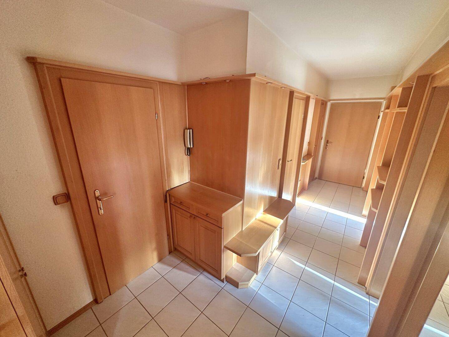 Heller Flur mit Einbauschränken aus Holz und Fliesenboden.