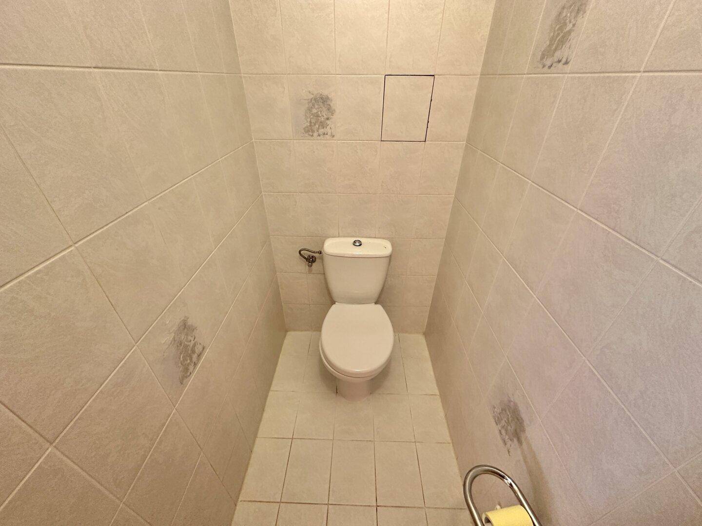 Separate Toilette mit hellen Fliesen und Standard-WC.