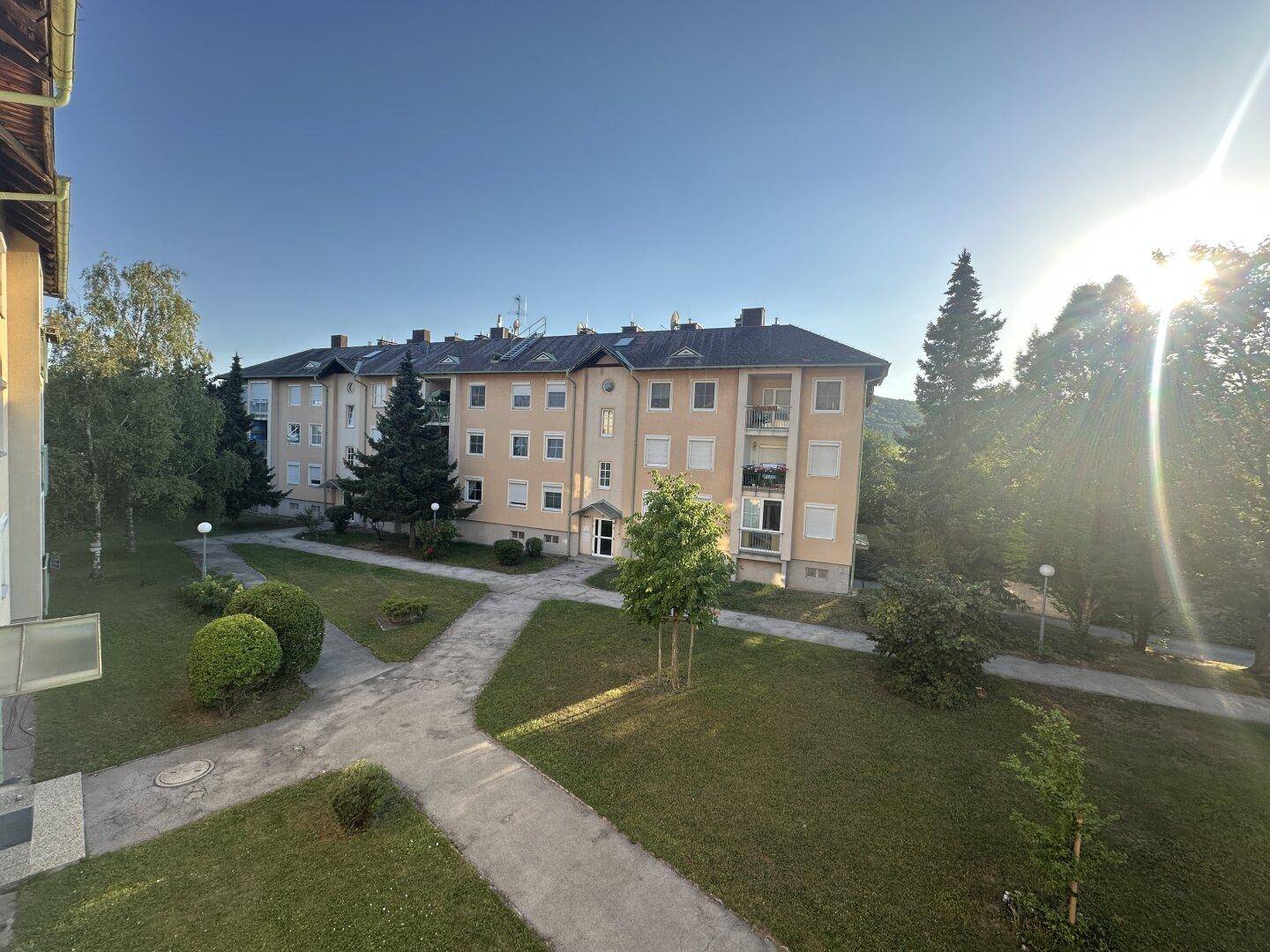 Wohngebäude mit gepflegter Grünanlage und Wegen im Innenhof.