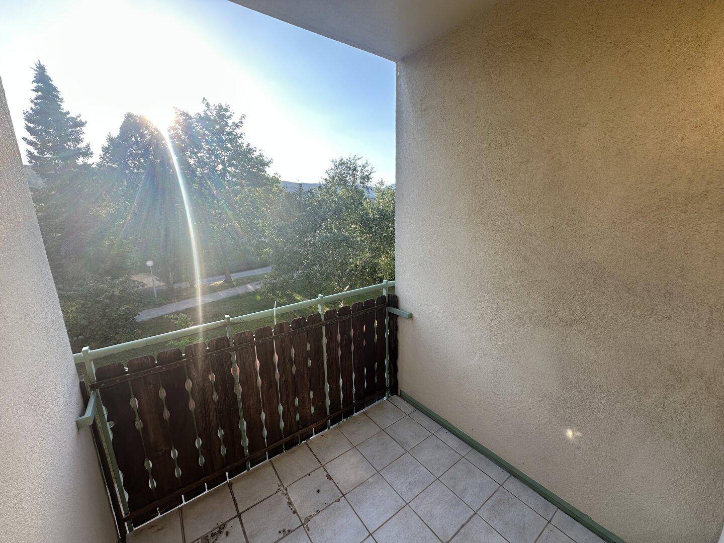 Sonniger Balkon mit Holzelementen und Blick ins Grüne.