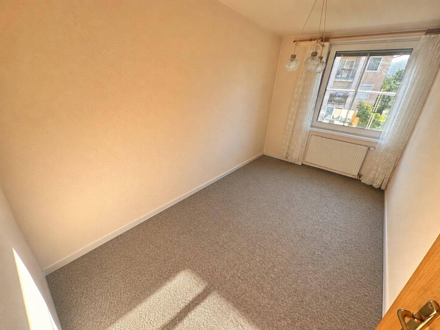 Kleines Zimmer mit Teppichboden und Fenster, ideal als Büro oder Kinderzimmer.