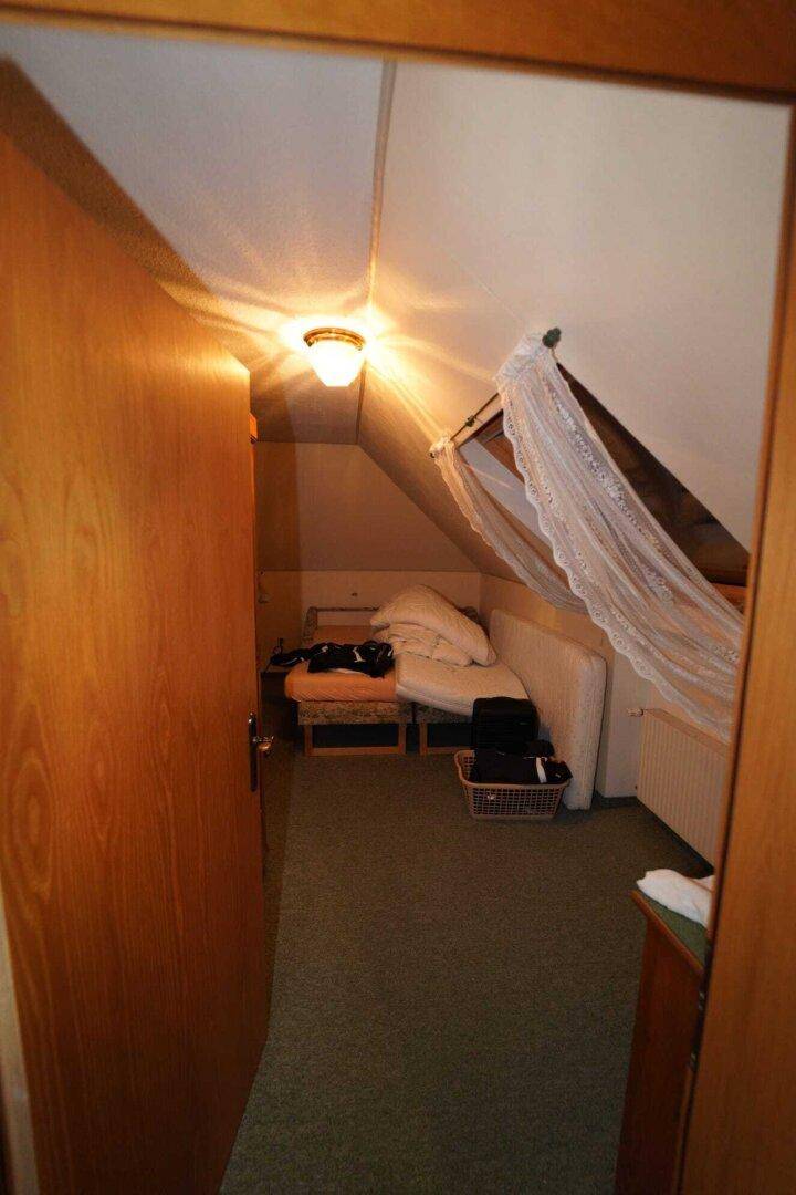 Ein weiterer Raum im Dachgeschoss mit schrägen Wänden und Teppichboden, möglicherweise als Gästezimmer.