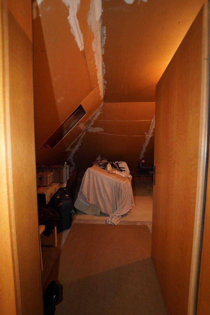 Ein weiterer Bereich im Dachgeschoss mit schrägen Wänden und Teppichboden, möglicherweise als Abstellraum.