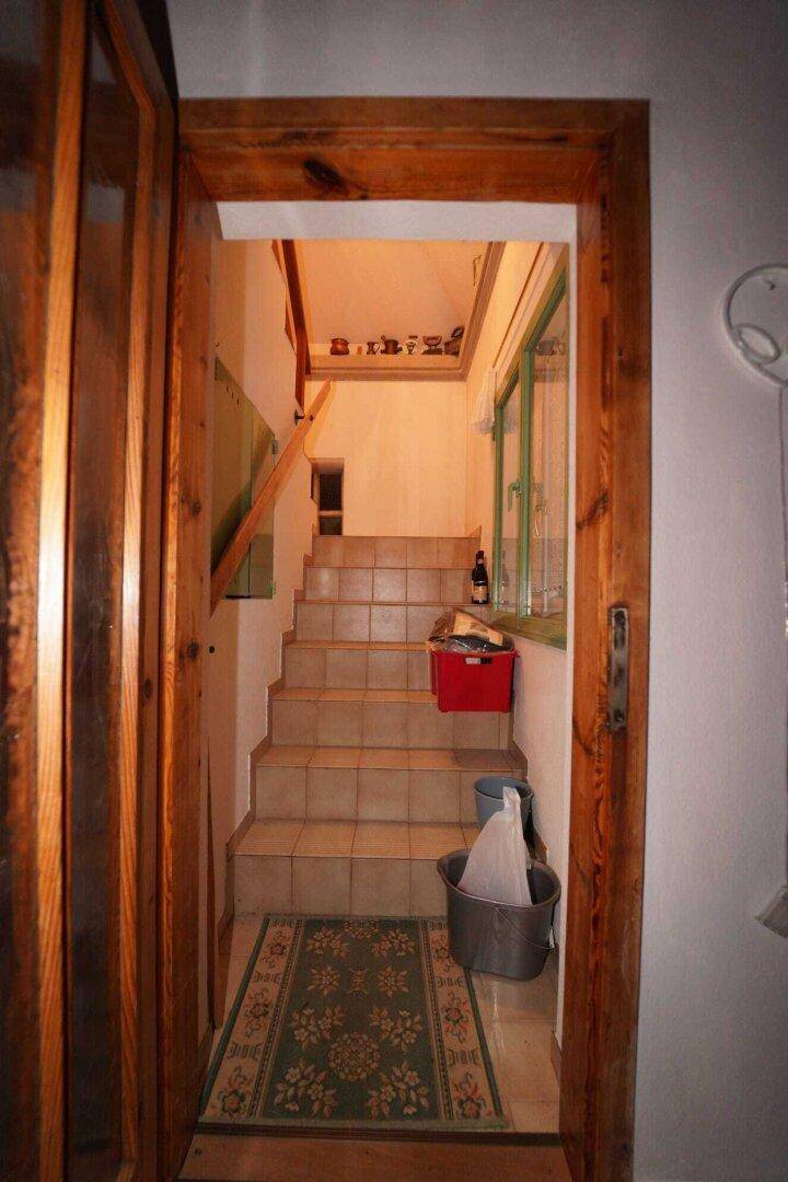 Eine geflieste Treppe führt in das obere Stockwerk, mit einem Fenster für natürliches Licht.